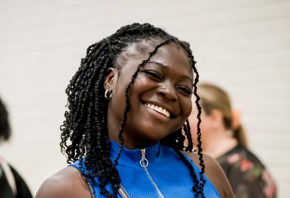 Une étudiante sur le campus portant un grand sourire.