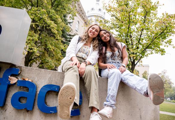 Deux étudiantes assisent sur le monument devant la façade de l'USB.