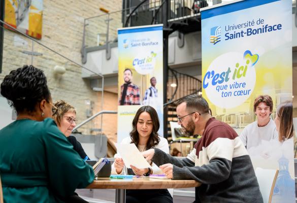 Des membres du personnel autour d’une table dans le Centre étudiant Étienne-Gaboury revoient ensemble des documents.