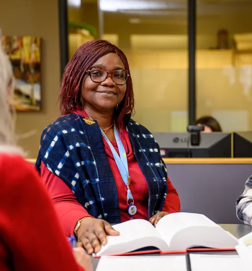 Quatres personnes souriantes sont assises à une table et consultent un dictionnaire pendant une discussion de groupe.