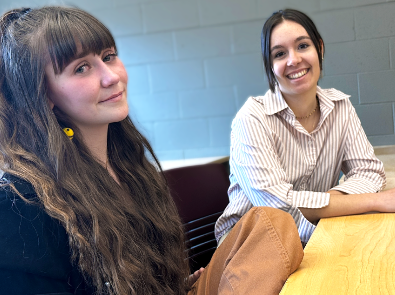 Portrait d’Anne-Sophie Régnier et Alexi Gagnon, souriantes, assises à une table lors de la Journée du Savoir à l’USB.