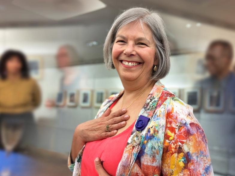 émue par sa nomination à titre d'Officier au sein de l'Ordre des Palmes académiques de la France, Lise Gaboury-Diallo sourit, entourée d'invitées et d'invités lors de la cérémonie de remise du prix.