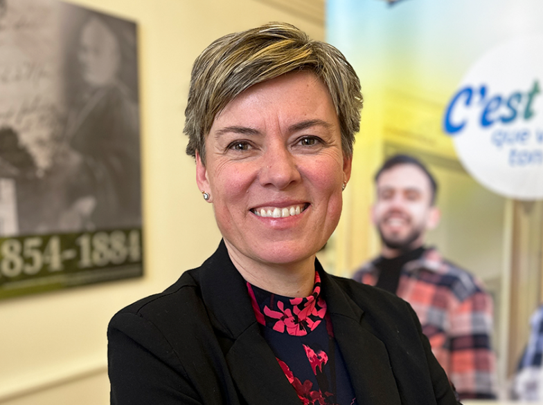 Lucile Griffiths sourit, en tenue professionnelle, devant des affiches de l’USB, après avoir reçu un prix national pour son engagement en formation.