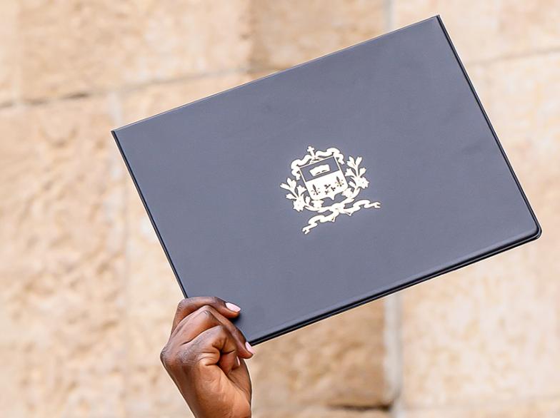Une main brandit un diplôme.