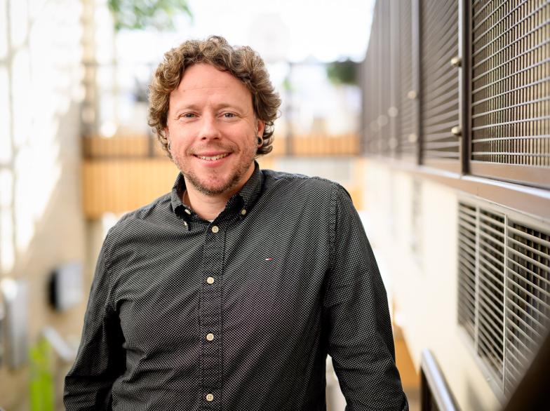 Le professeur de philosophie Antoine Cantin-Brault, dans l'escalier au pavillon Marcel-A.-Desautels, sourit en fixant l'objectif.