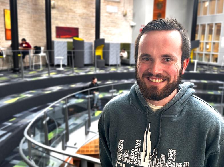 Pierre Courchaine, étudiant à l’USB et représentant jeunesse de Développement et Paix, sourit dans l’Agora du campus, un espace moderne et lumineux
