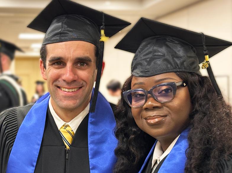 Deux diplômés souriants portant toge noire, épitoge bleue et mortier traditionnel en préparation à la cérémonie de collation des grades, d’autres finissantes et finissants en arrière-plan.