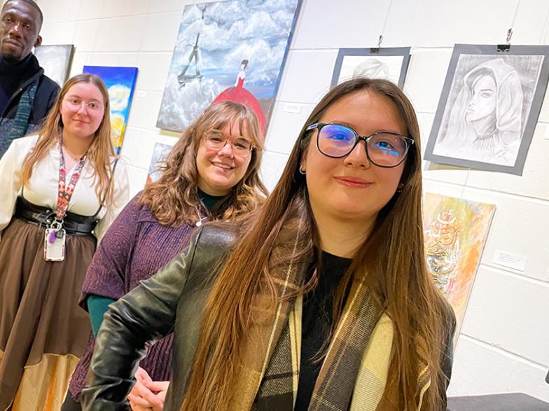 Quatre artistes étudiants posent fièrement devant leurs œuvres exposées à la Galerie de l’USB.