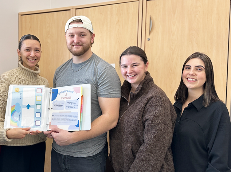 Six étudiantes et étudiants souriants présentent un cartable d’outils pédagogiques colorés destiné à l’accompagnement des enfants autistes.