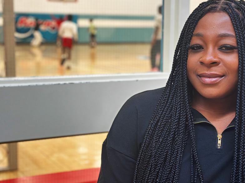 Stéphanie Koudou, assise à la vitrine offrant un aperçu d'activités sportives dans le gymnase.