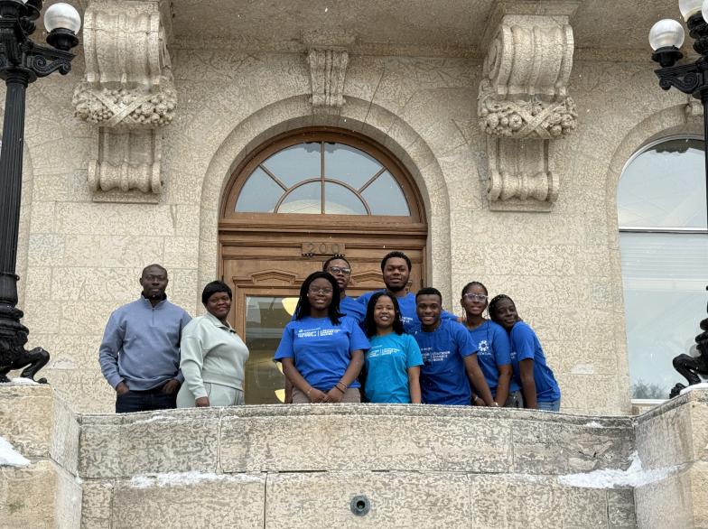 Des étudiantes et étudiants devant une façade de bâtiment portent fièrement un chandail bleu du club EUMC.