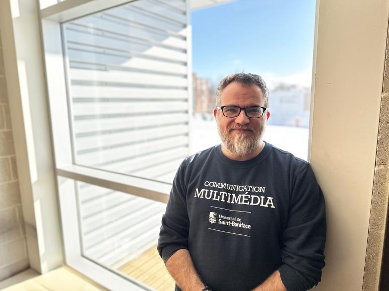 Frédéric Jubinville, prof en communication multimédia, près d'une fenêtre qui laisse entrer la lumière.