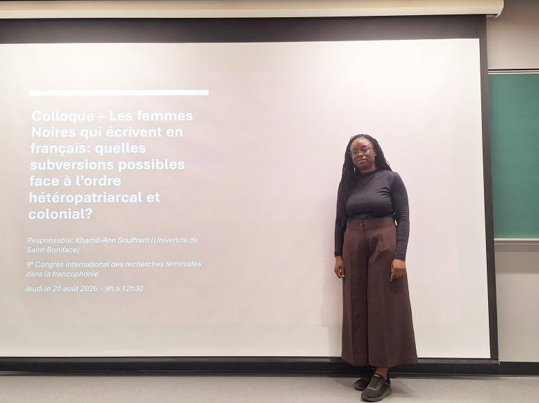 Debout devant un grand écran, Kharoll-Ann Souffrant, professeure à l'École de travail social, donne une conférence lors d'un colloque sur les recherches féministes.