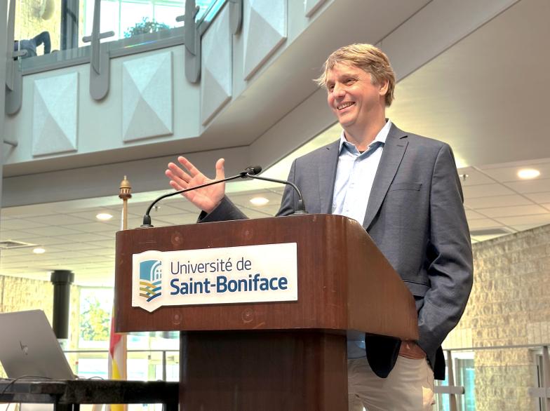 Étienne Rivard derrière un podium adresse la foule au centre étudiant Étienne-Gaboury.