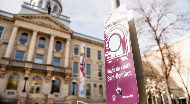 Devant la façade de l'USB un jour de printemps, un panneau indique la Route du vieux Saint-Boniface.