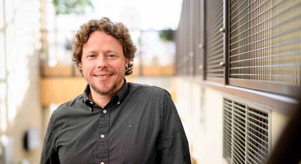 Le professeur de philosophie Antoine Cantin-Brault, dans l'escalier au pavillon Marcel-A.-Desautels, sourit en fixant l'objectif.