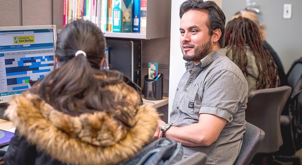 Un conseiller discute avec une étudiante dans un bureau.