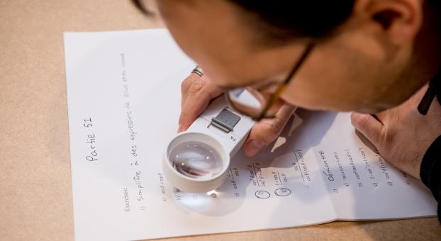 Mise au point sur une loupe utilisée par un étudiant malvoyant pour lire le texte sur une feuille de travail.