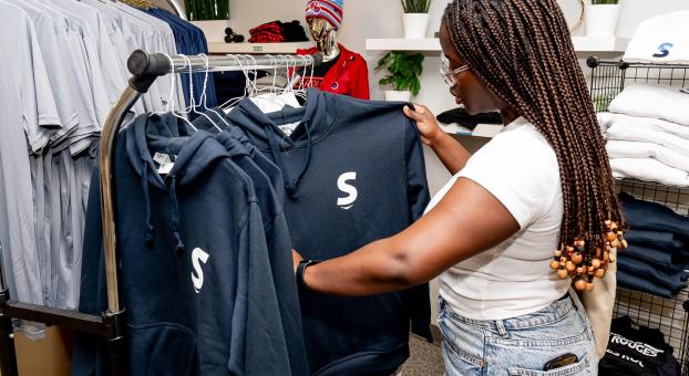 Une étudiante regarde les chandails « hoodies » à vendre dans la Boutique.