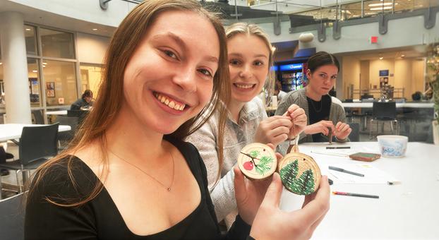 Des étudiantes participent à un AtelYé créatif à l’Université de Saint‑Boniface en décorant des ornements en bois.