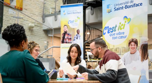 Des membres du personnel autour d’une table dans le Centre étudiant Étienne-Gaboury revoient ensemble des documents.