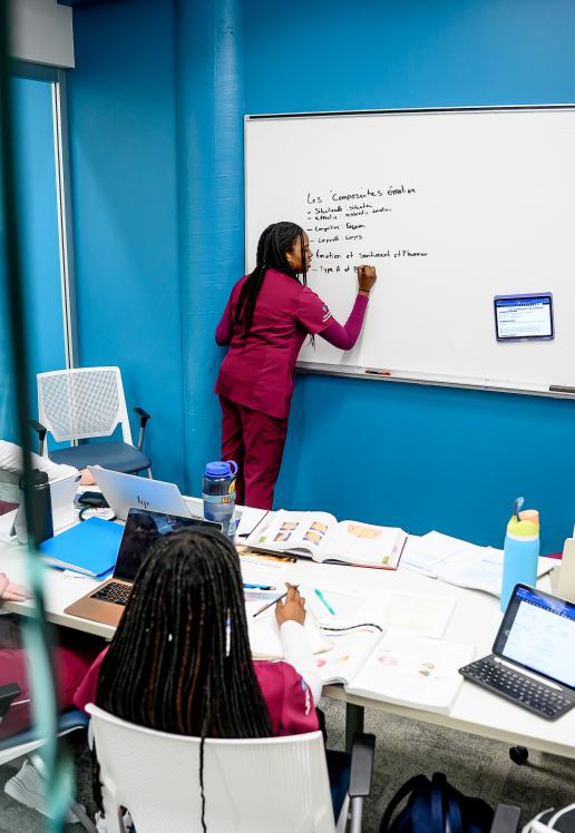 Cinq personnes en vêtements de soins infirmiers revoient leurs notes de cours ensemble dans une salle de travail de groupe à la bibliothèque de l’USB.