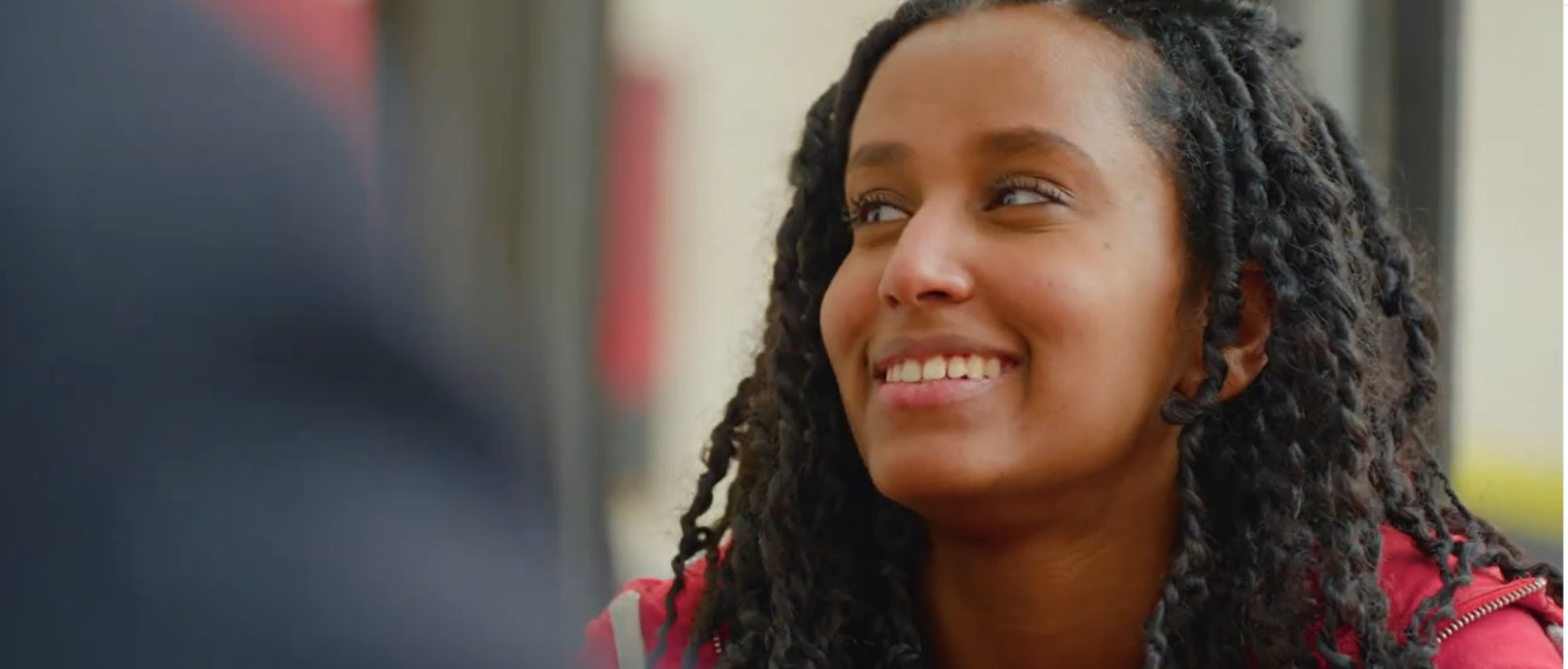 Gros plan sur le visage d'une étudiante souriante aux cheveux noirs tressés.