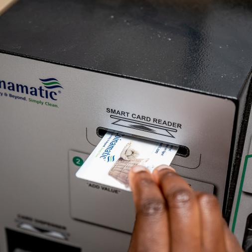 Une main insère une carte dans un lecteur de cartes intelligentes sur une machine de lessive.