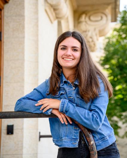 Une jeune femme aux cheveux mi-longs châtain et blond, les mains jointes sur une table ronde, regarde l’objectif en souriant.