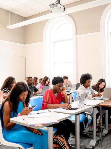 Dans une salle de classe éclairée, des personnes prennent des notes.