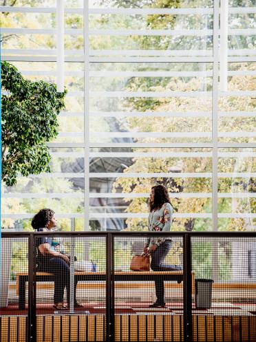 Deux personnes jasent près d’une fenêtre dans l’environnement lumineux du pavillon Marcel-A.-Desautels.